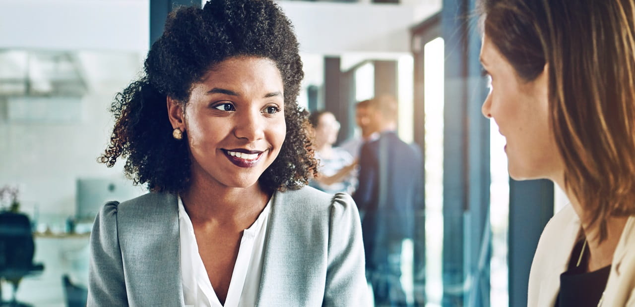Two businesswomen speaking in an office.