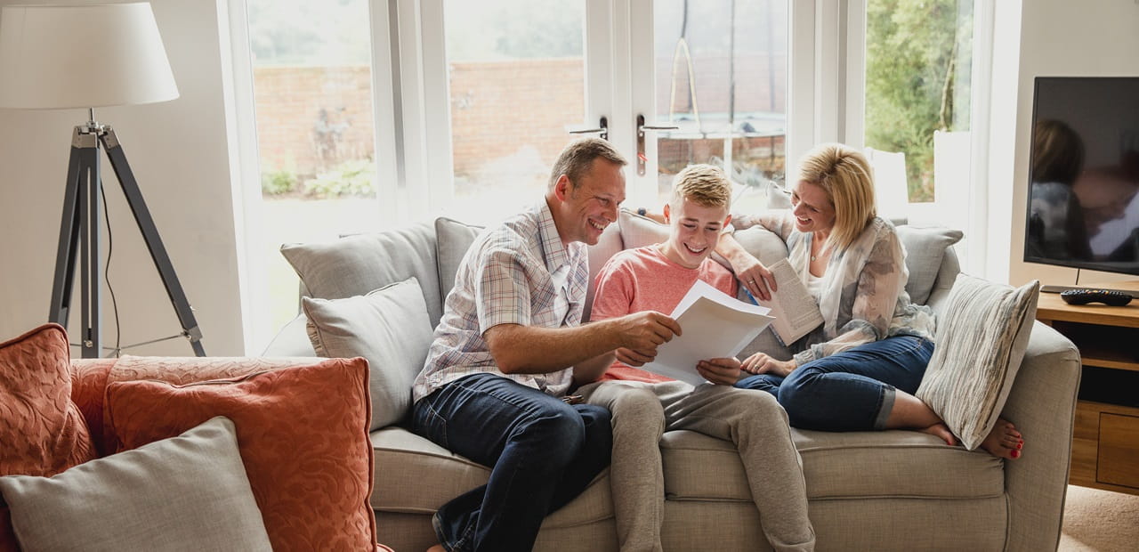 A teenage boy reads his exam results with his parents.
